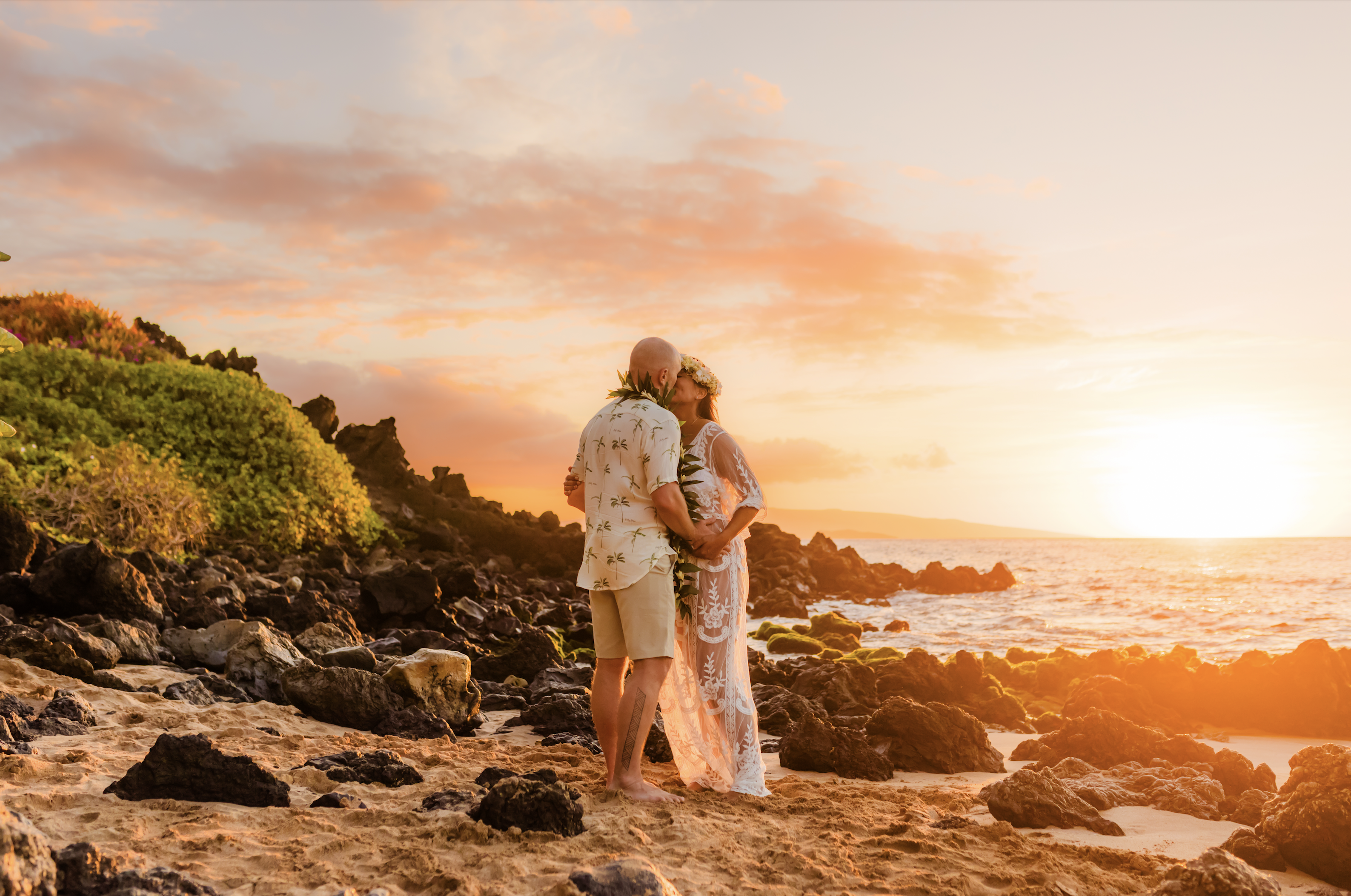 couple kiss at sunset, woman is pregnant and celebrating a maui vow renewal in wailea